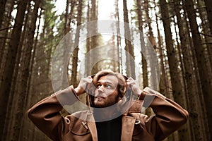 Portrait of a young handsome man, with a mysterious look, in a dark wild forest.