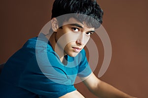 Portrait of young handsome man posing on studio bsckground looking to camera