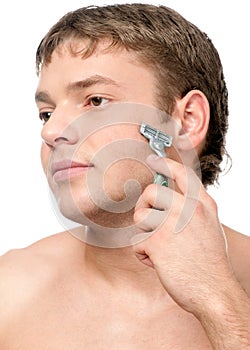 Portrait of a young handsome man shaving