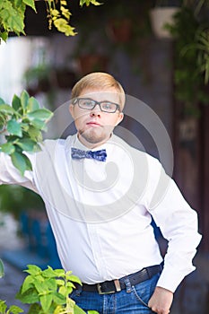 Portrait of young handsome man with short hair wearing a bow tie and posing in the city streets.