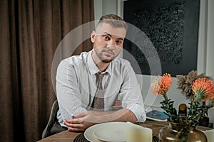 Portrait of a young handsome man sitting at the yable during romantic dinner at homne