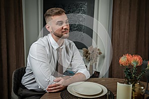 Portrait of a young handsome man sitting at the yable during romantic dinner at homne