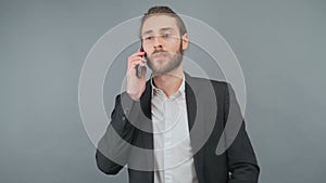 Portrait of young handsome man, talking on the phone, holding smartphone next to ear, answering call, isolated on gray