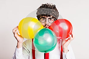 Portrait of a young man with balloons in a studio.