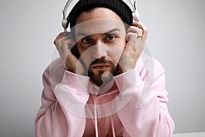 Portrait of a young handsome man with toupee and headphones in white background