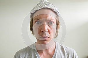 Face of young man wearing tin foil hat inside the room photo
