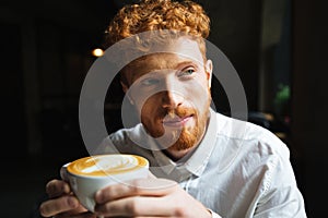 Portrait of young handsome readhead bearded man in white shirt h