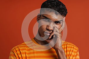 Portrait of young handsome serious african man touching his face