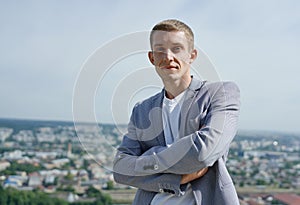 Portrait of young handsome serious businessman on city background