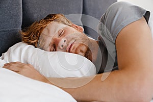 Portrait of young handsome sleeping redhead man in gray t-shirt