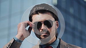 Portrait of Young Handsome Successfull Bussinessman in a Suit Wear Sunglasses Standing near modern Office Centre Close