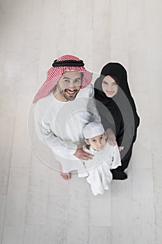 Portrait of a young happy Arabian Muslim family couple with a son in traditional clothes spending time together