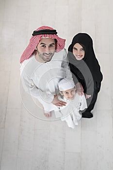 Portrait of a young happy Arabian Muslim family couple with a son in traditional clothes spending time together