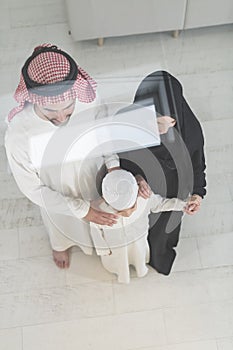 Portrait of a young happy Arabian Muslim family couple with a son in traditional clothes spending time together