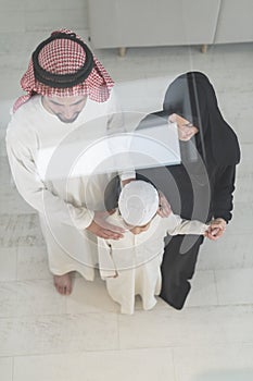 Portrait of a young happy Arabian Muslim family couple with a son in traditional clothes spending time together