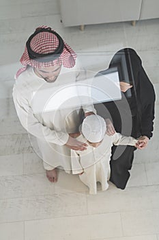 Portrait of a young happy Arabian Muslim family couple with a son in traditional clothes spending time together