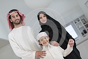 Portrait of a young happy Arabian Muslim family couple with a son in traditional clothes spending time together