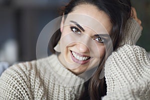 Portrait of a young happy beautiful woman in warm clothings at home