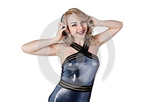 Portrait of Young happy blonde woman dressed in latex swimsuit listen to music at black wireless headphones, isolated on white