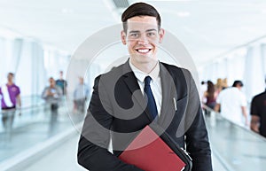 Portrait of young happy businessman in front of busy modern background.