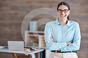 Portrait of a young happy cheerful mixed race businesswoman wearing her spectacles smiling while standing with her arms