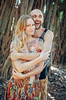 Portrait of young happy couple on blurred natural background. Attractive guy and his girlfriend hugging and smiling while looking