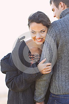 Portrait of young happy couple laughing in a cold day by the autumn sea