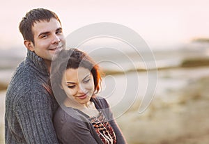Portrait of young happy couple laughing in a cold day by the aut
