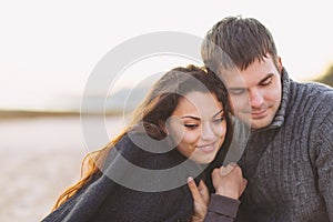 Portrait of young happy couple laughing in a cold day by the aut