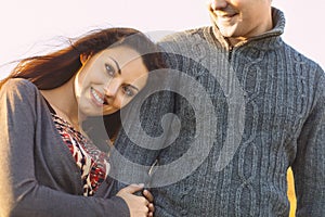 Portrait of young happy couple laughing in a cold day by the aut