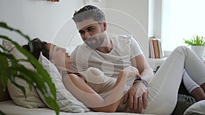 Portrait of young happy couple is talking while lying on bed in white bedroom spbd.