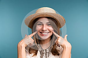 Portrait of a young happy girl in summer hat isolated over blue background