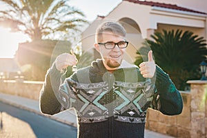 Portrait of a young happy man holding out new house key and gesturing thumbs up