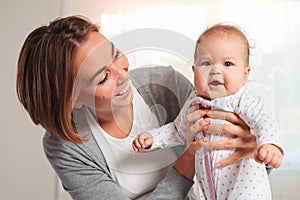 Portrait of a young happy mother holding her cute baby in her hands. Concept of motherhood and child care