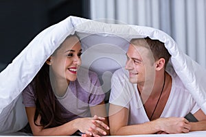 Portrait of young happy playful couple relaxing in comfortable cozy bed