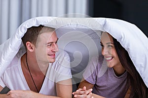 Portrait of young happy playful couple relaxing in comfortable cozy bed