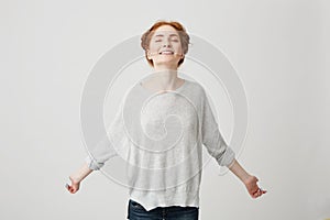 Portrait of young happy redhead girl smiling with closed eyes over white background.