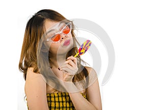 Portrait of young happy and Asian Korean girl in cool fashion sunglasses eating lollipop candy posing naughty teasing