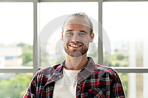 Portrait of young happy short stylish bearded caucasian man or creative designer smiling and looking at camera