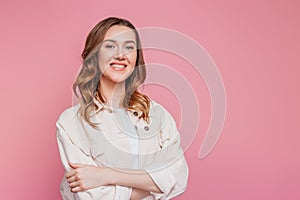 Portrait of a young happy smiling caucasian student girl with wavy hair in a beige corduroy jacket isolated on pink background,