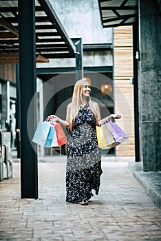 Portrait of young happy smiling woman with shopping bags walking