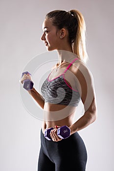 Portrait of young happy smiling woman in sportswear, doing fitness exercise with dumbbell over white background
