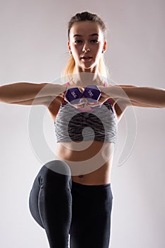 Portrait of young happy smiling woman in sportswear, doing fitness exercise with dumbbell over white background