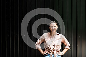 Portrait of young happy woman with cool attitude outdoor with black wall background in the summer. Sensuality and fashion