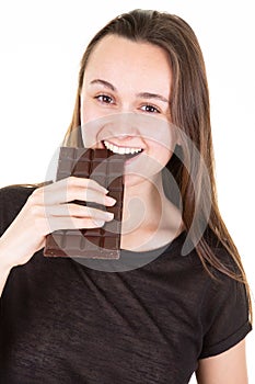 Portrait of young happy woman eating bar chocolate looks in camera