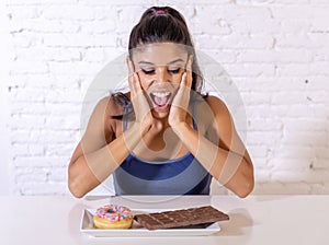 Portrait of young happy woman eating delighted chocolate bar and donuts