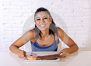 Portrait of young happy woman eating delighted chocolate bar and donuts