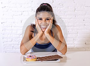 Portrait of young happy woman eating delighted chocolate bar and donuts