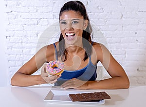 Portrait of young happy woman eating delighted chocolate bar and donuts