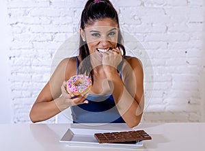 Portrait of young happy woman eating delighted chocolate bar and donuts